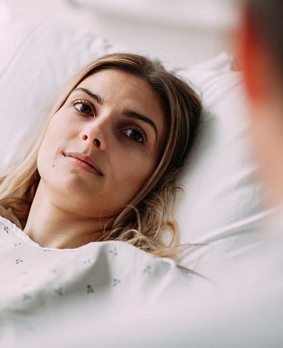 Patient lying in bed and listening to a healthcare professional speaking to her