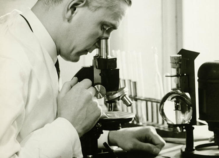 Scientist looking through a microscope in Baxter's earlier days