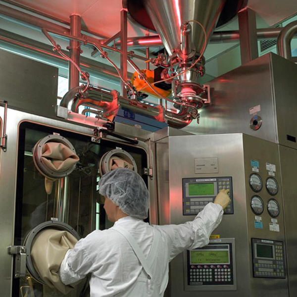 A worker performing a procedure in a sterile crystallization manufacturing area